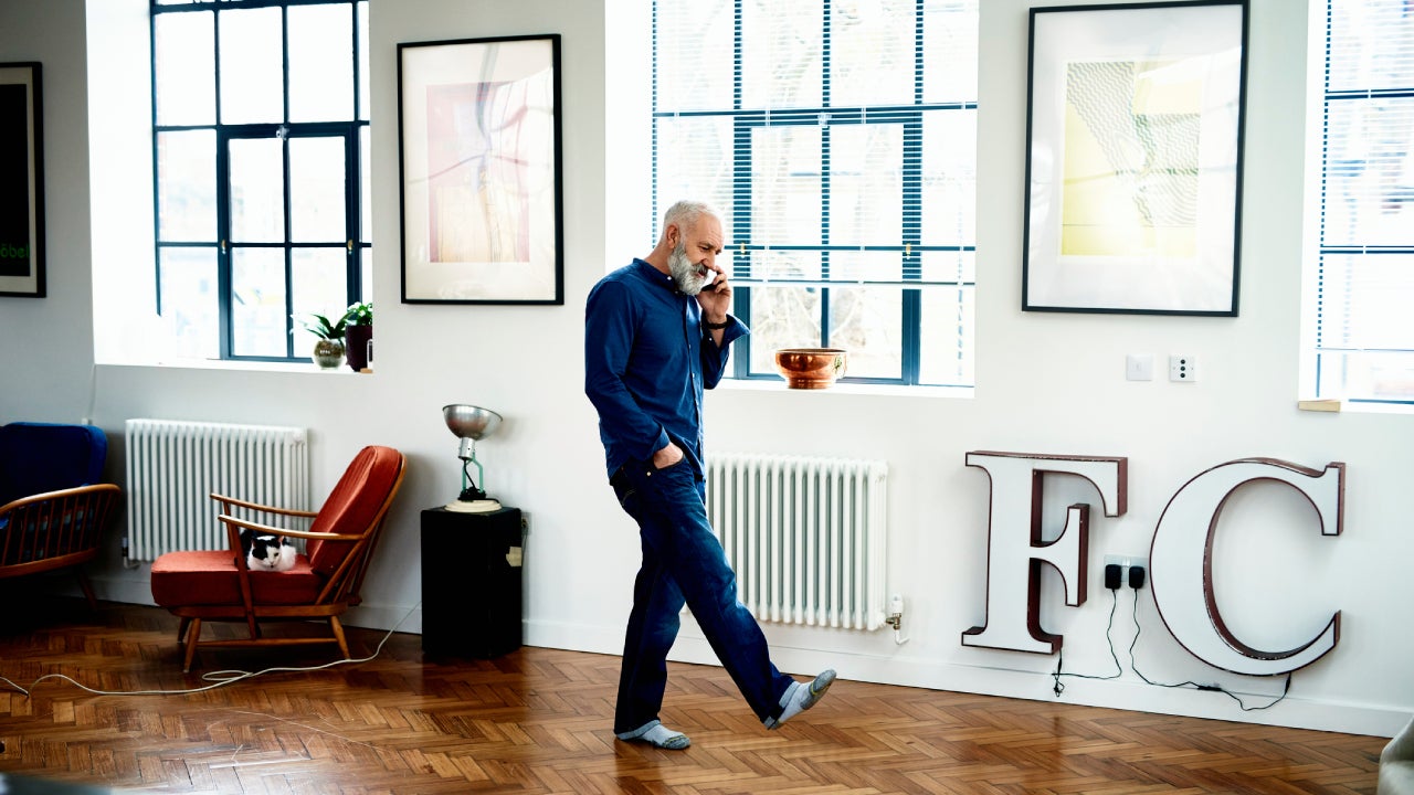 Hipster senior man on cell phone in funky apartment