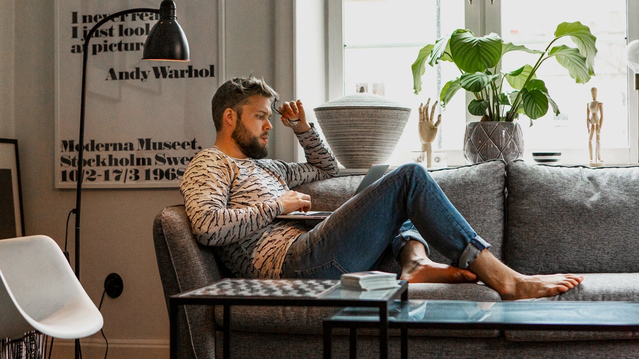 young person sitting on their couch on their computer