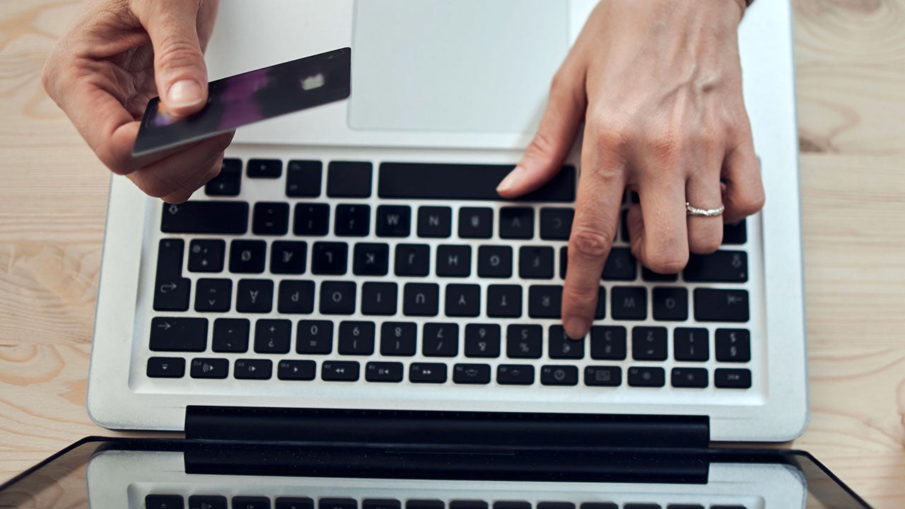 close up of woman's hand typing on a laptop and holding a credit card