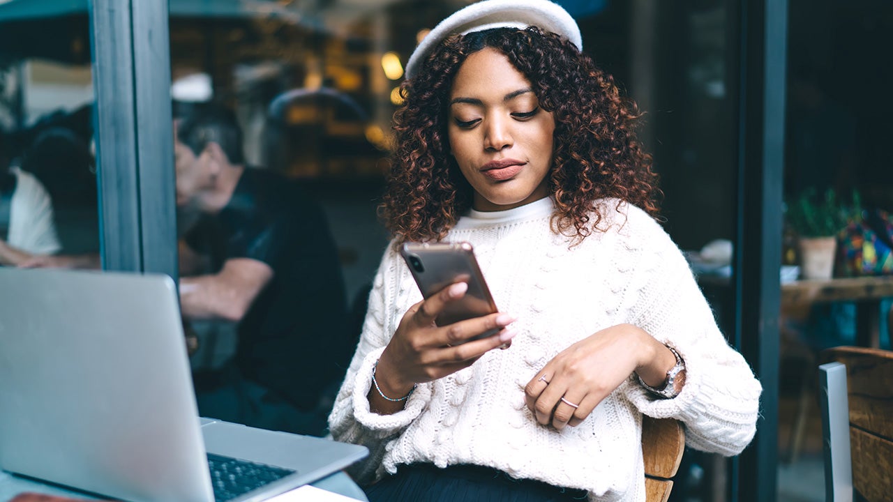 Woman sitting outside of restaurant looking at cell phone