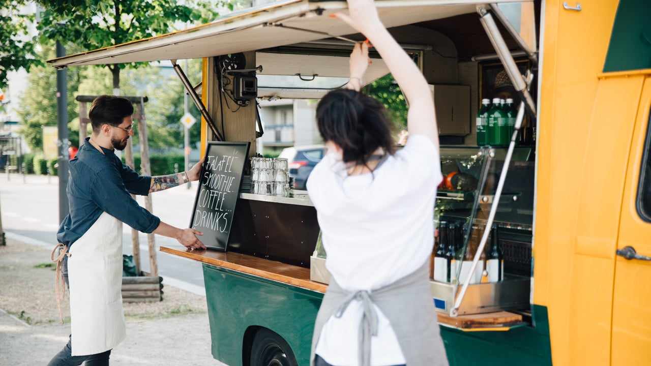 man and woman opening the side window of a food truck