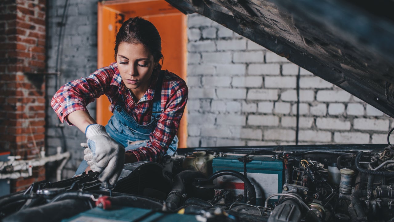 Female mechanic working on engine in a brick garage