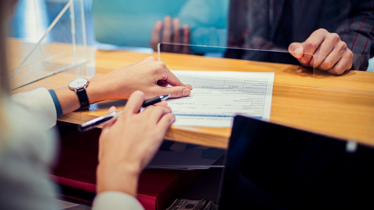 close up of bank teller's hands giving paperwork to a customer