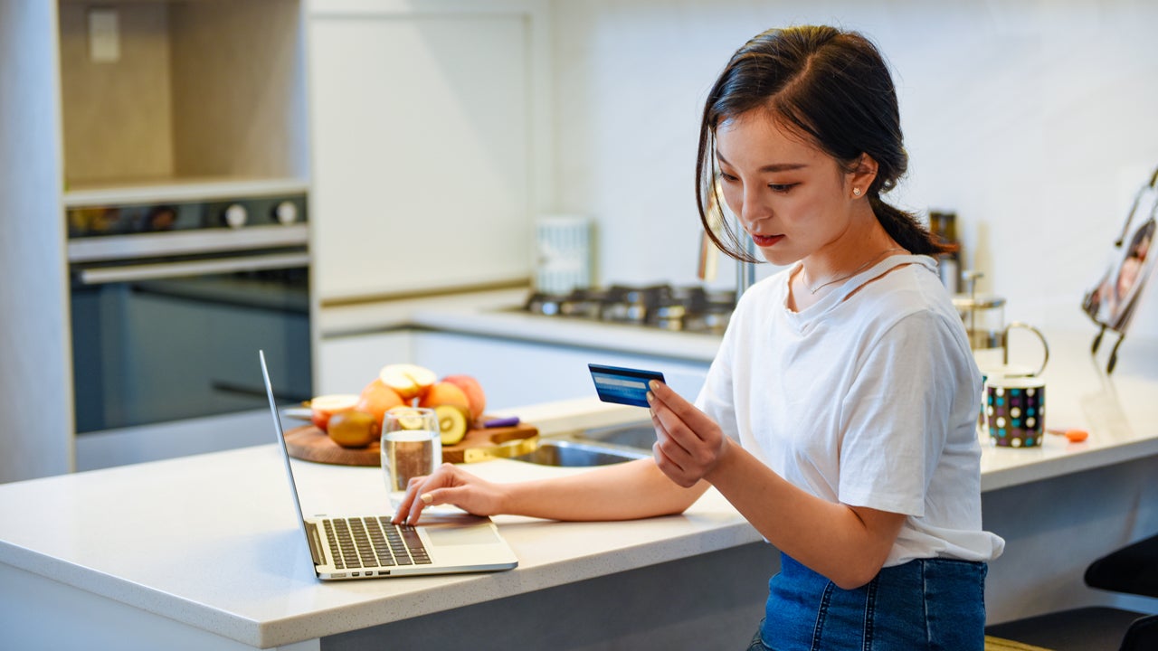 woman looking at credit card and typing on computer