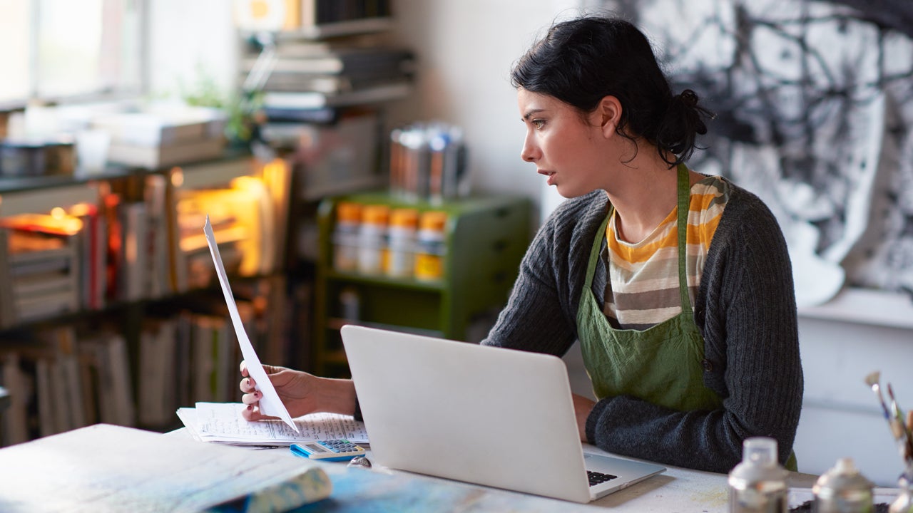 artist in her studio working on paperwork and her laptop