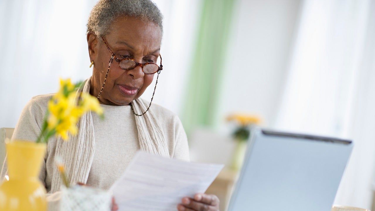 Woman looking at paperwork and her computer screen