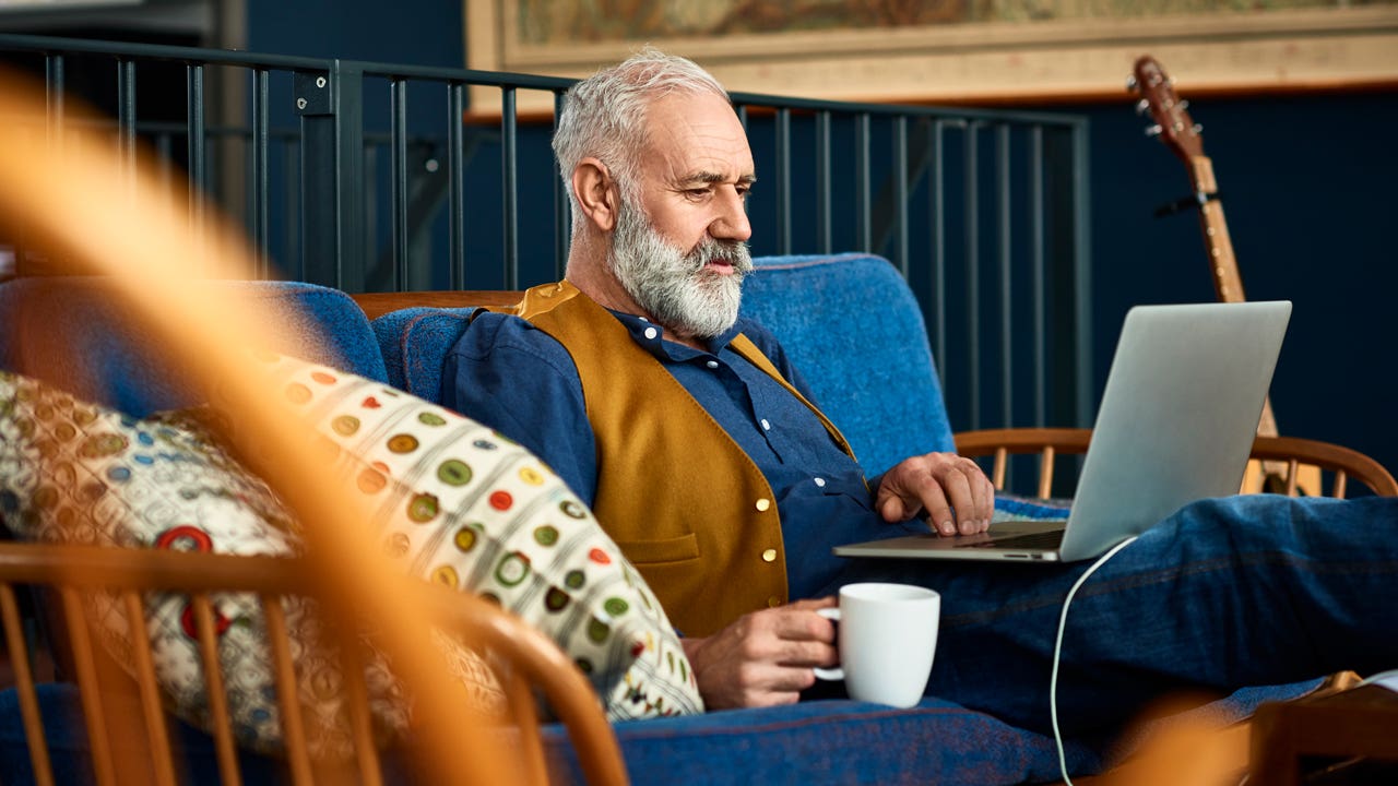 man sitting on the couch at home working on his laptop