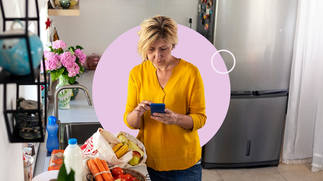 A woman looking at her phone with groceries sitting nearby