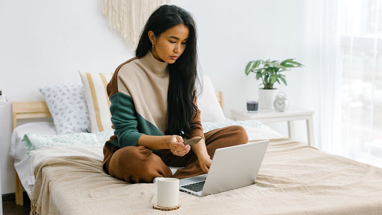 woman on her computer holding a card