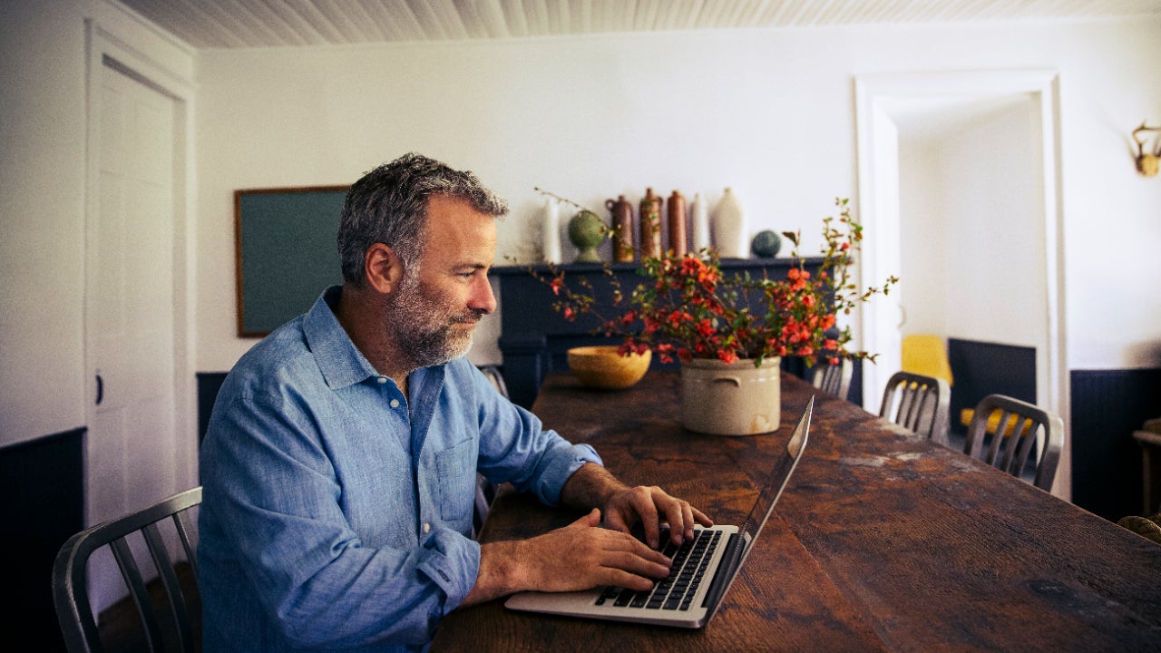 Man sitting at dining room table on laptop