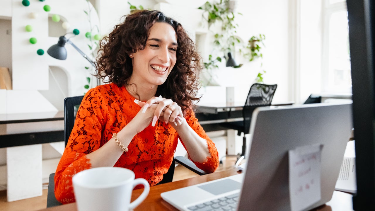 A smiling woman sits at her office desk