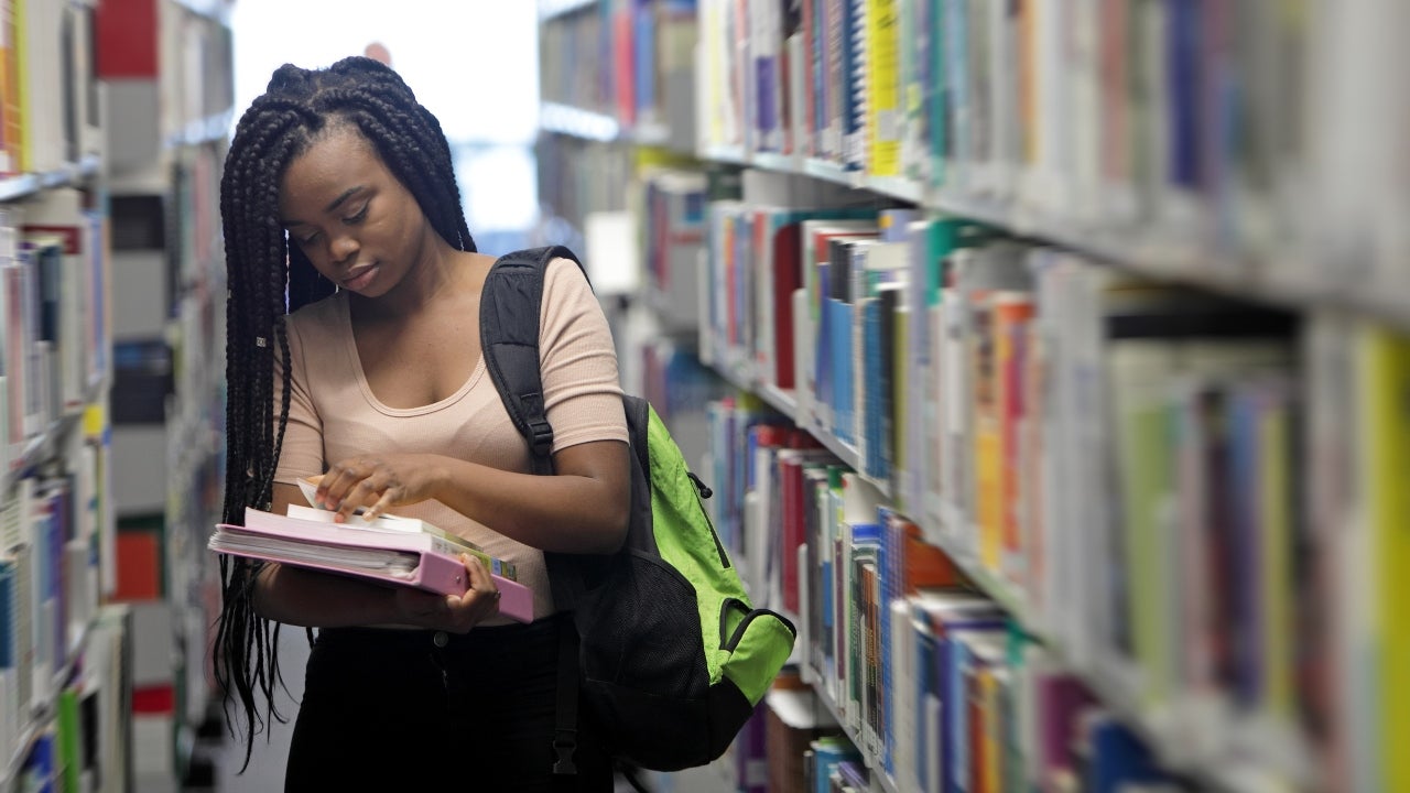 College student looks at books in the library