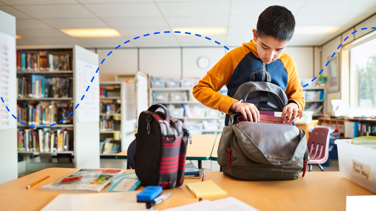 a kid packing things into his bookpack