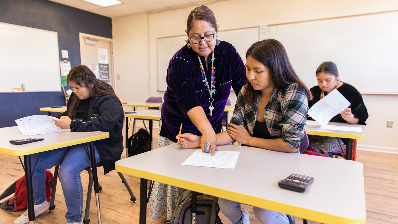 teacher helping student in a classroom