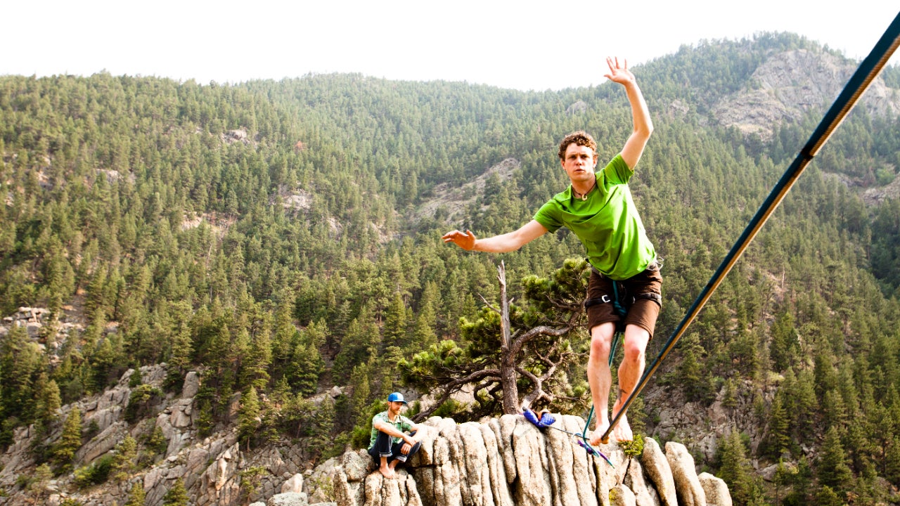 A man walks on a tightrope over a gorge