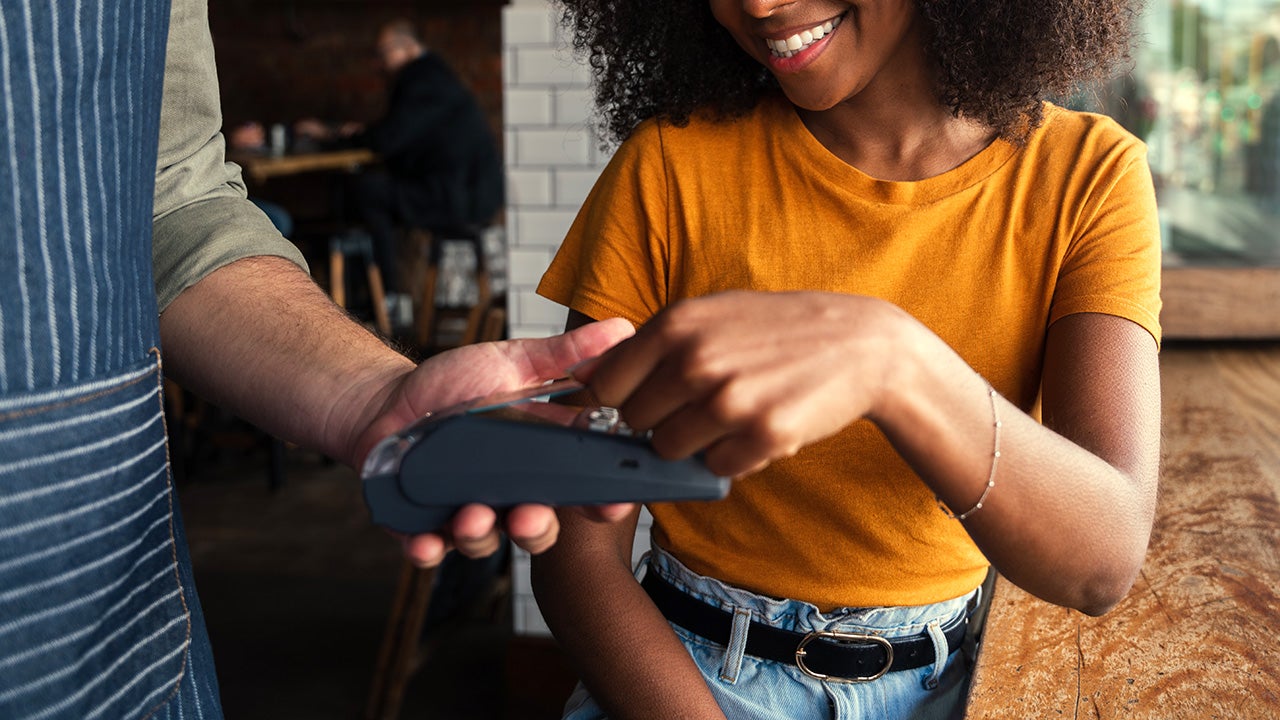 Smiling mixed race woman with afro happily paying for coffee at coffee shop