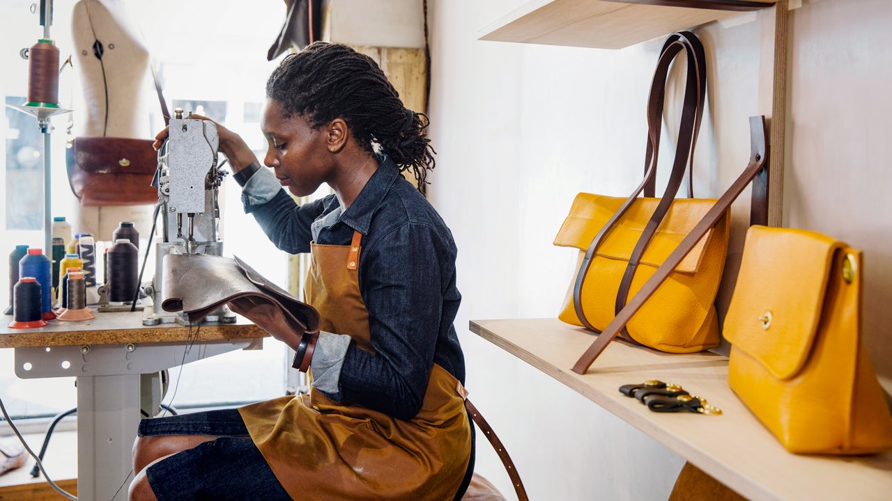 a women is sowing leather in a shop