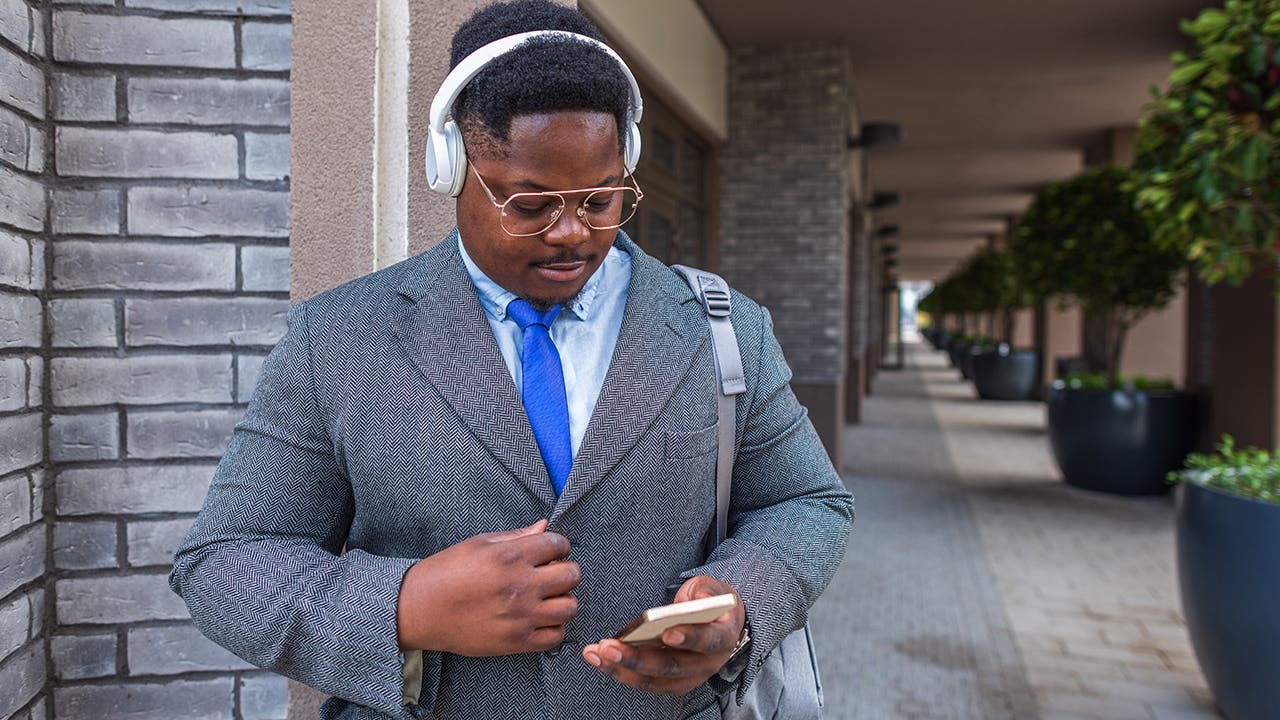 African young businessman with headphones on the street