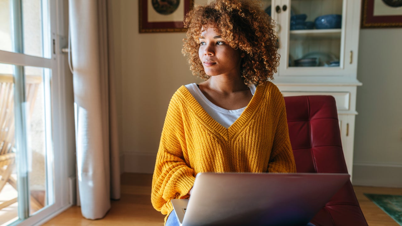 Young woman sitting on chaiselongue using laptop at home