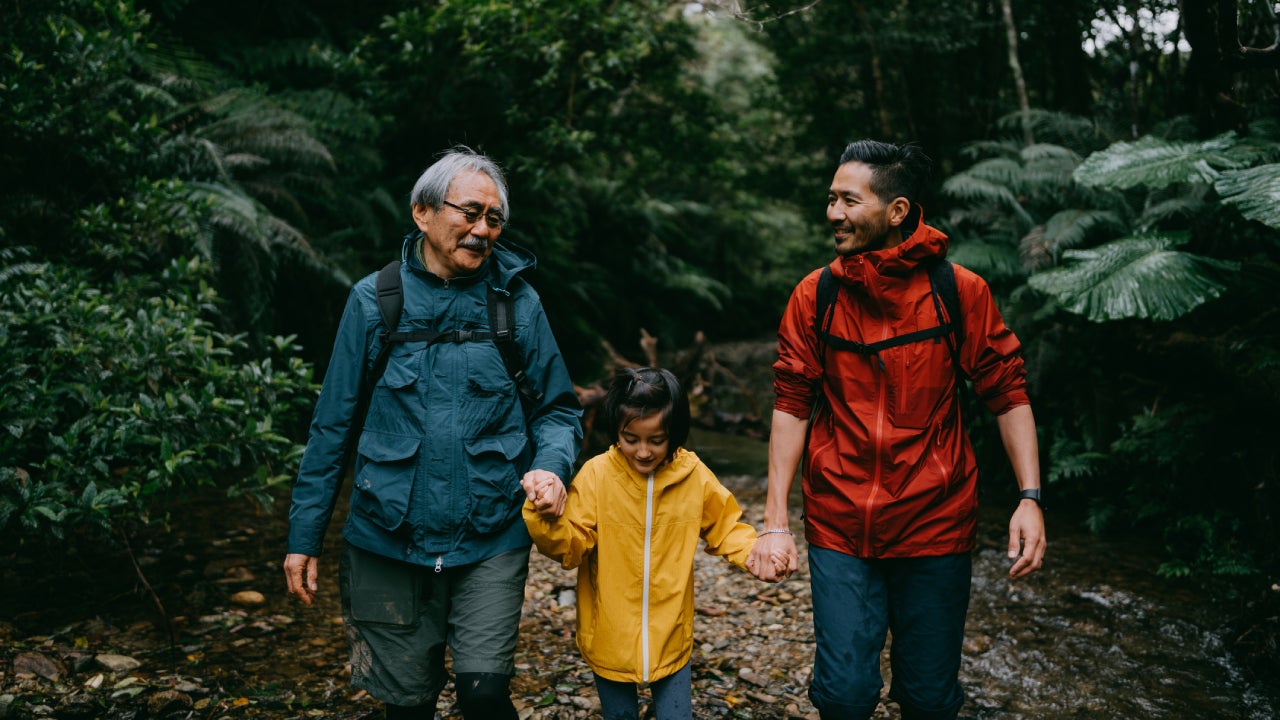 Three generation family hiking in rainforest in rain