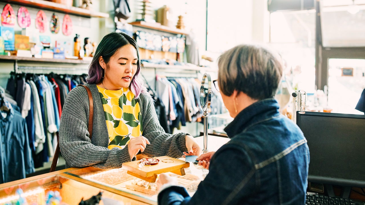 woman looking at jewelry in a store while talking to shop owner