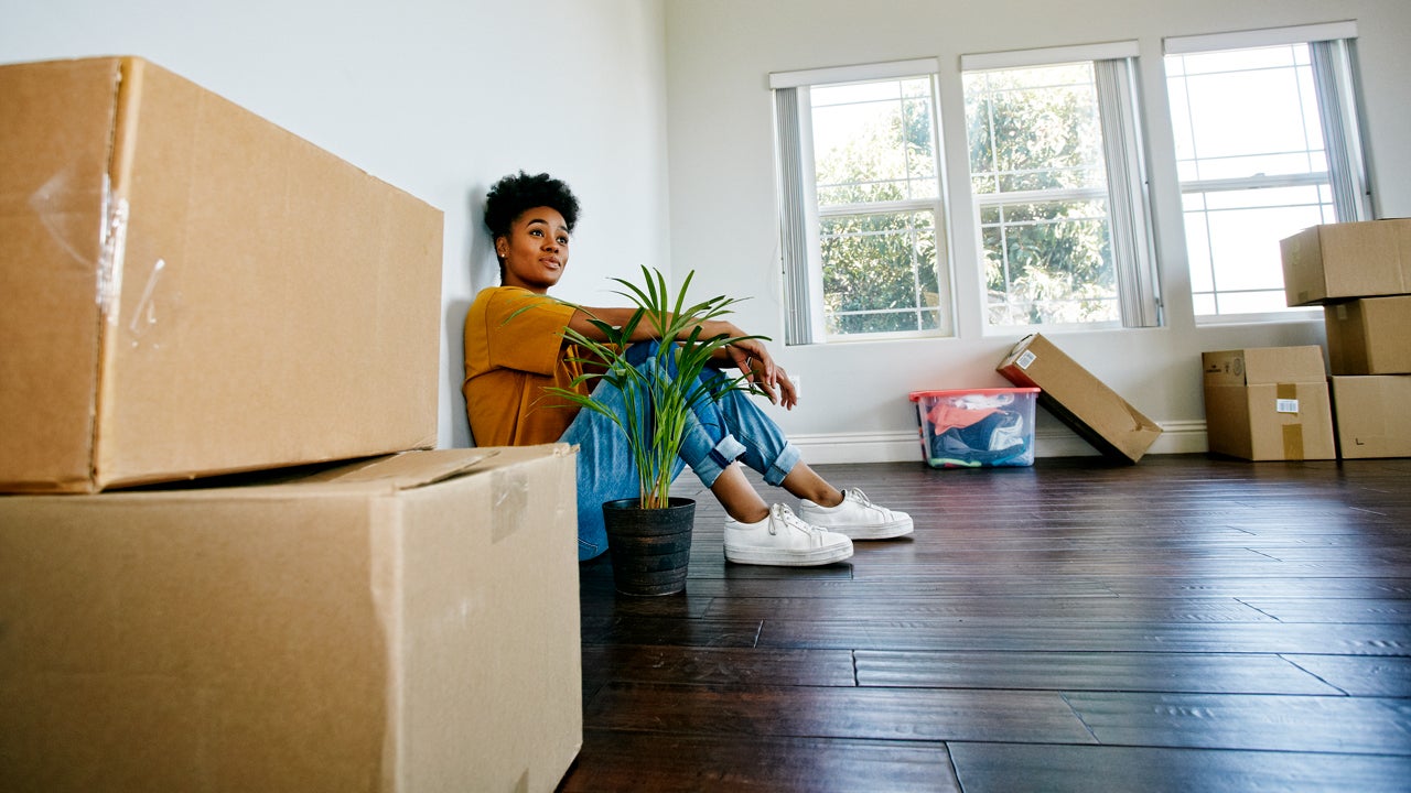 woman sitting on the floor in her new house with boxes around her