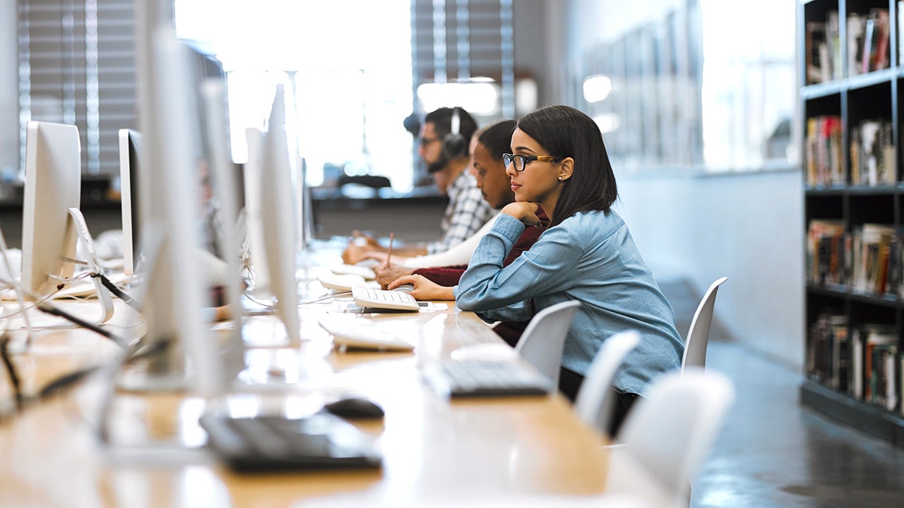 Shot of a group of university students working on computers in the library at campus