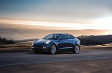 A blue 2022 Tesla Model 3 driving down the highway