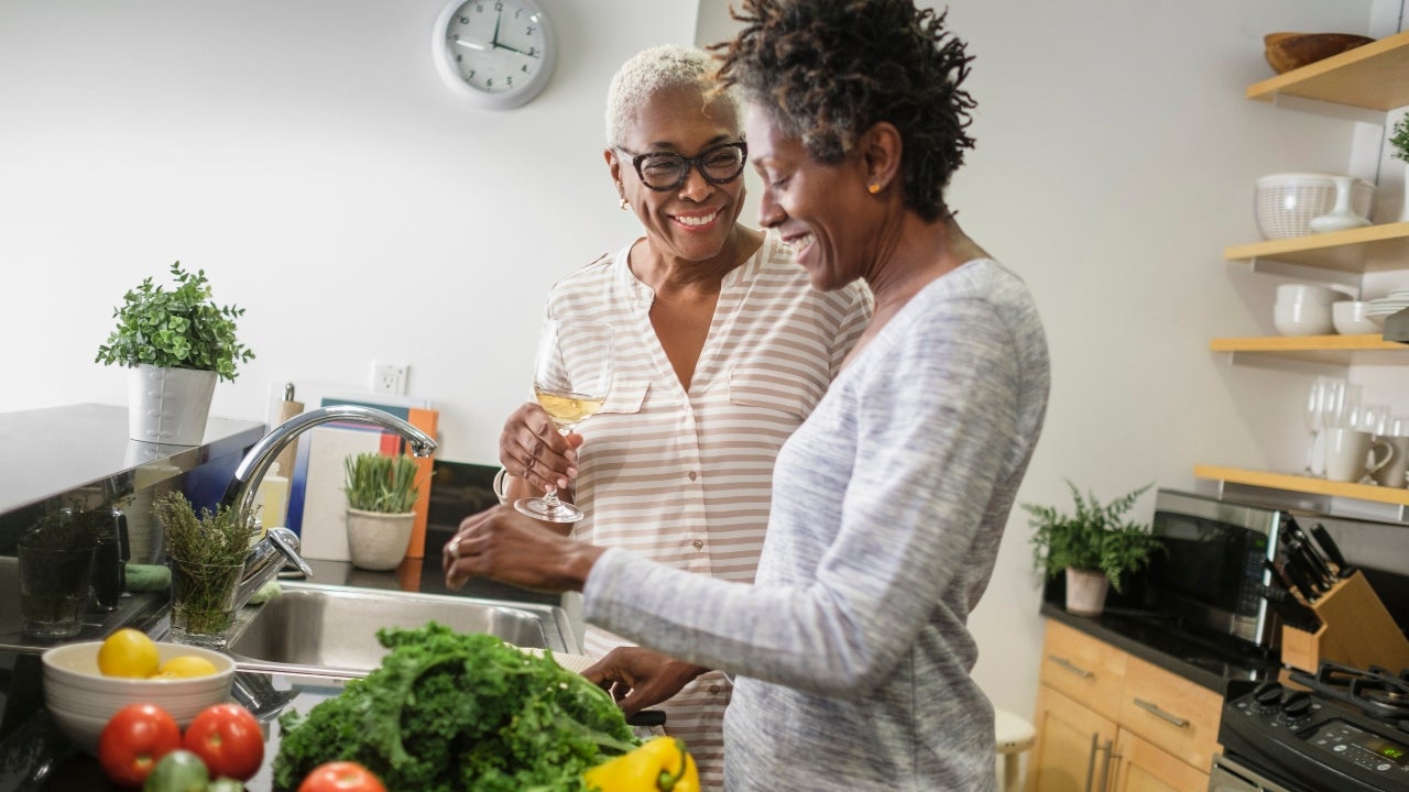 Two smiling Black women cook together.