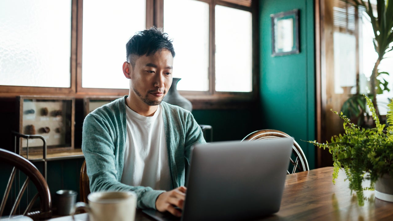 Young professional man working on a laptop in a cozy space with coffee