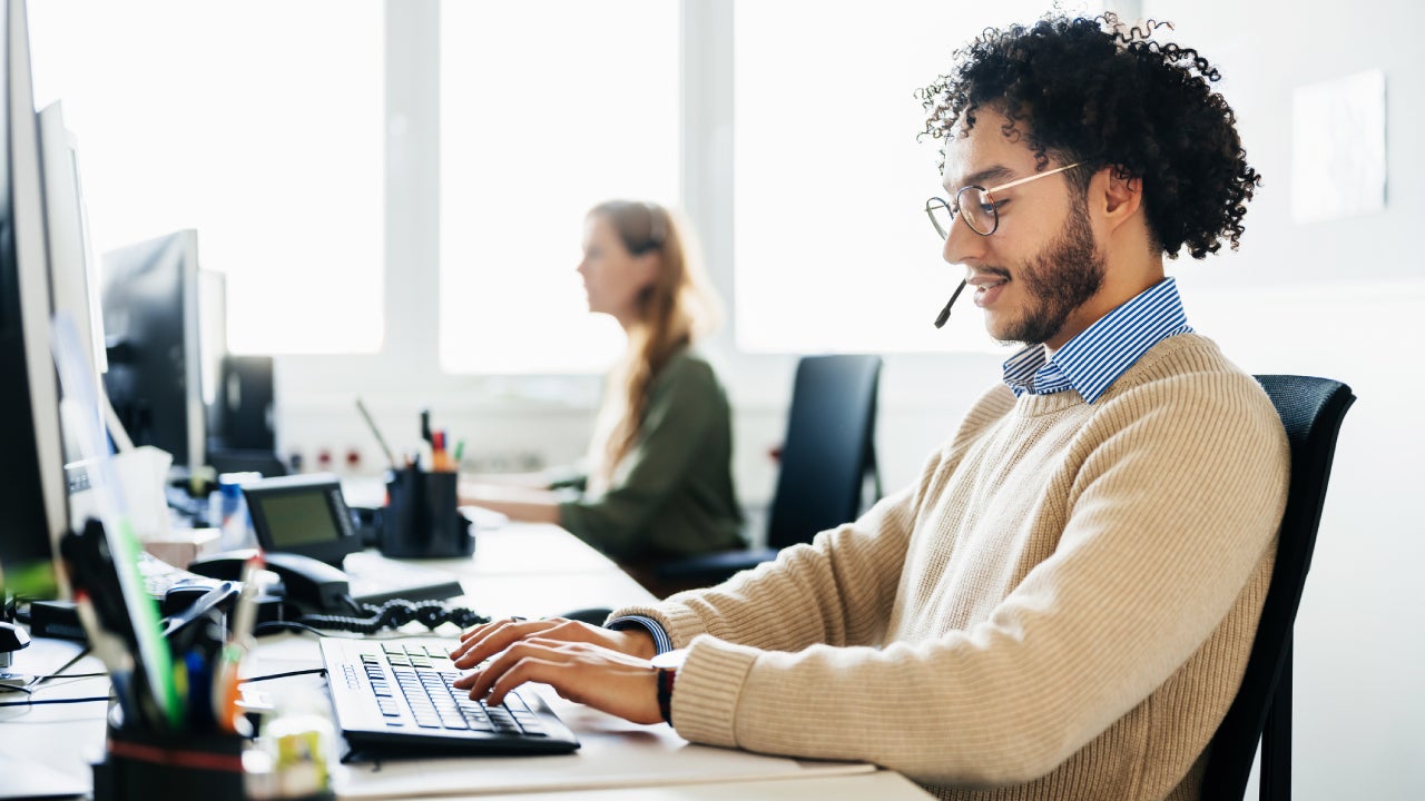 Man Working At Computer And Talking To Clients On Phone