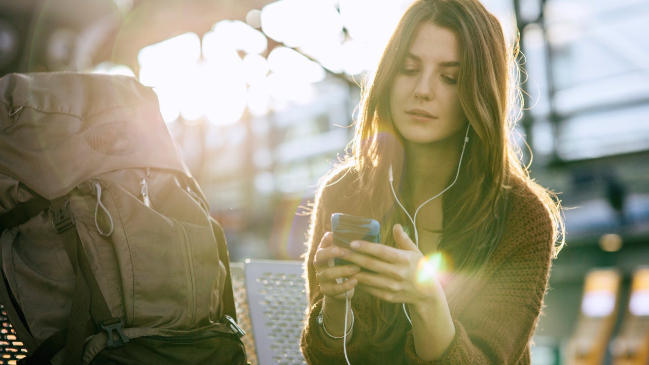 Young Backpacker With Smart Phone At Airport