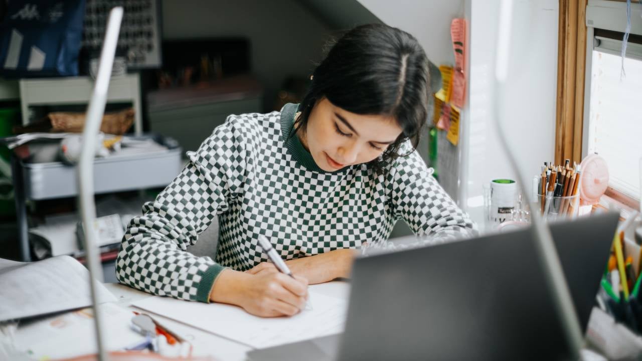 Hispanic latina college student works on assignment in her dorm room