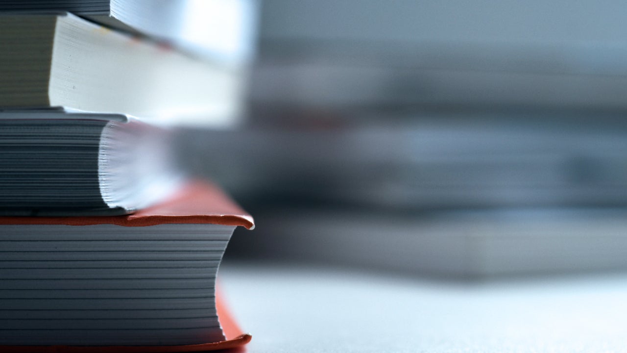 An in-focus stack of books mostly out of frame with a blurry stack of books behind it