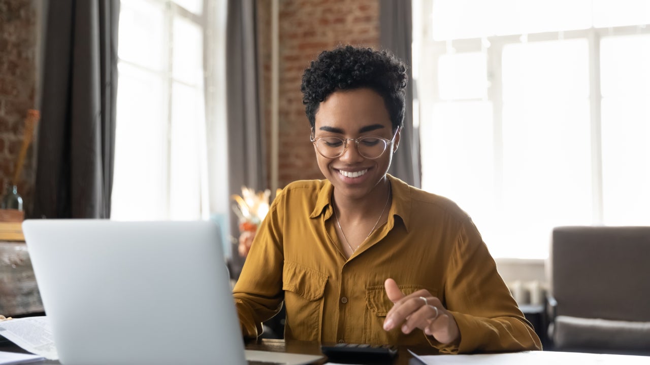 Happy young entrepreneur woman in glasses counting profit