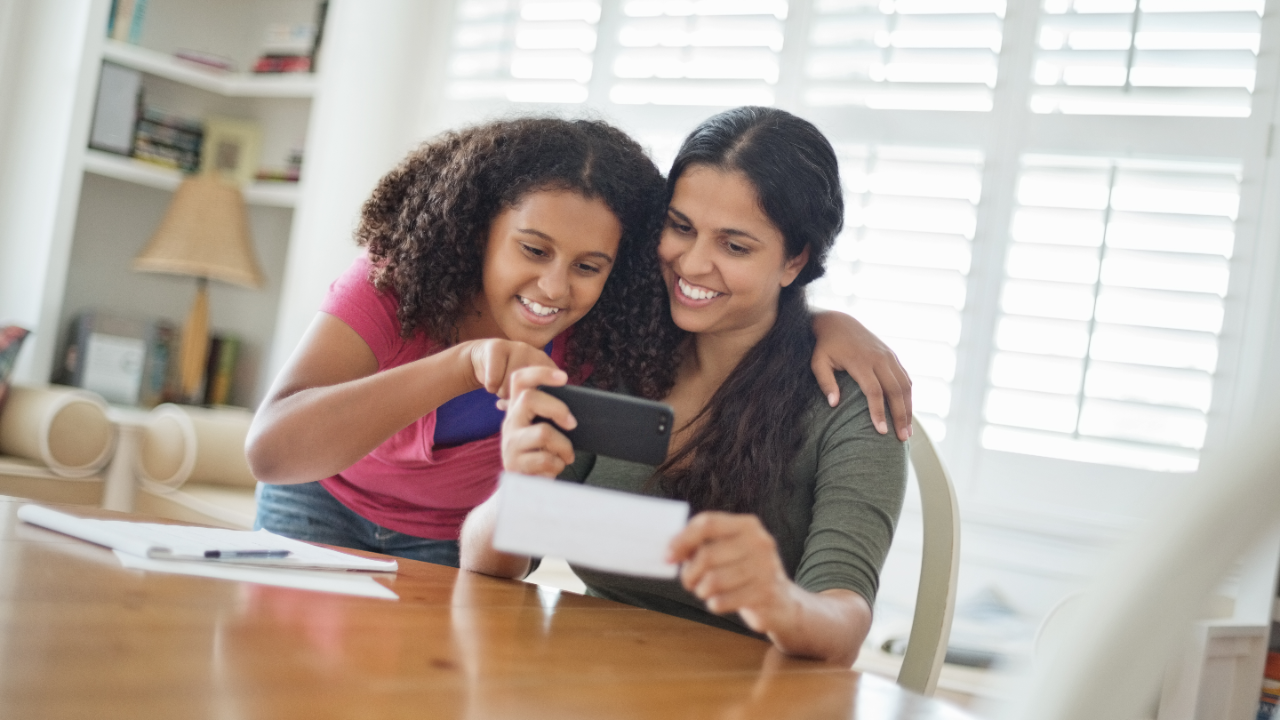 Mother and daughter smiling at smartphone