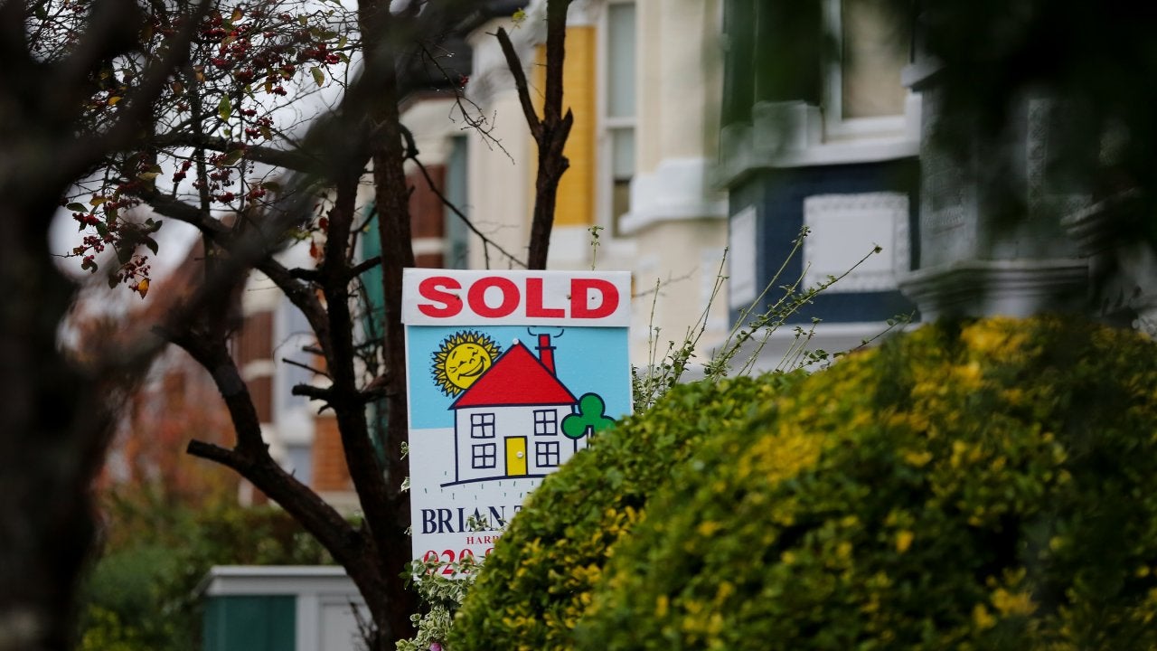 A "Sold" real estate sign tucked between bushes