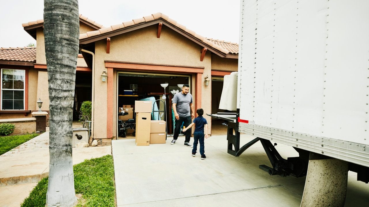 Young son helping father move items from moving truck into new house