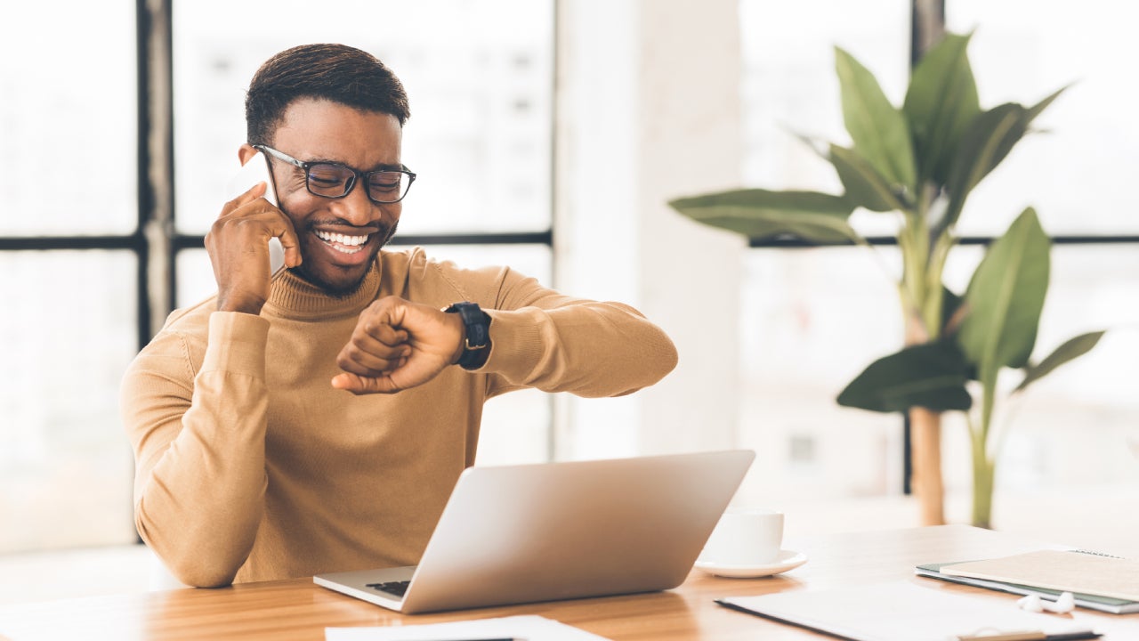 Happy guy looking at watch talking on phon