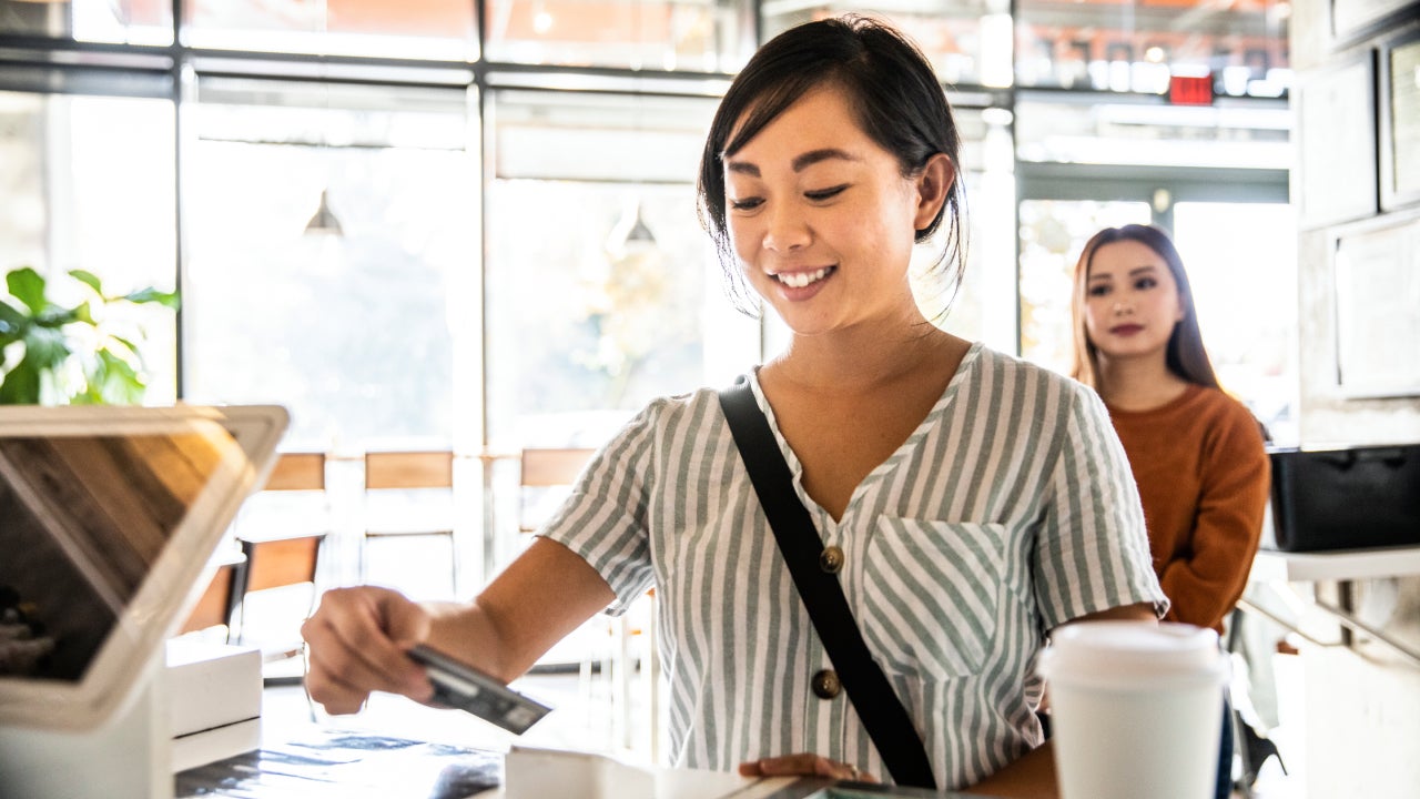 Young woman using credit card reader at coffee shop counter