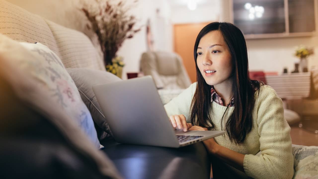 Woman working on laptop by the sofa in living room