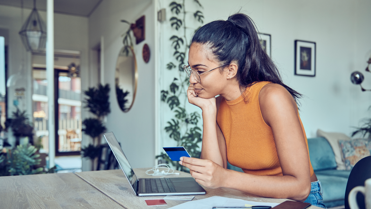 A woman is sitting at a dining table with a laptop and financial statements. Calculates and pays taxes and bills online.