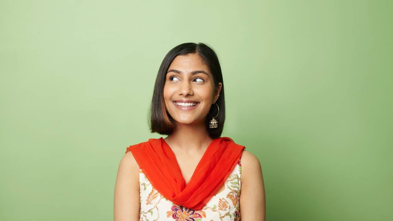 South asian woman looking to side against green background