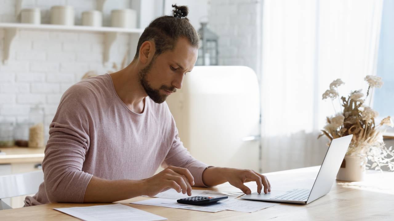 Focused young man managing household budget alone at home.