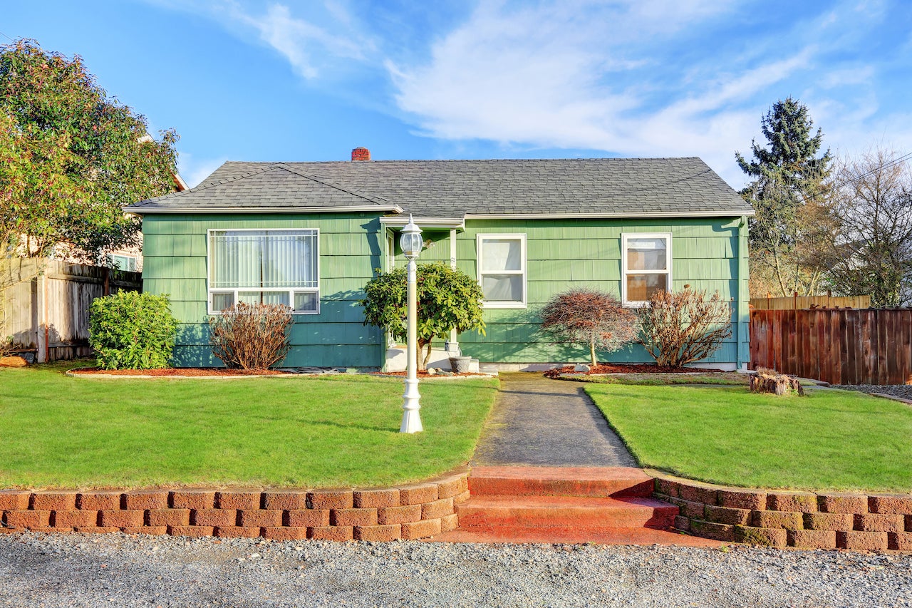 government sponsored enterprise - green bungalow style house with landscaping and blue sky and white lamppost