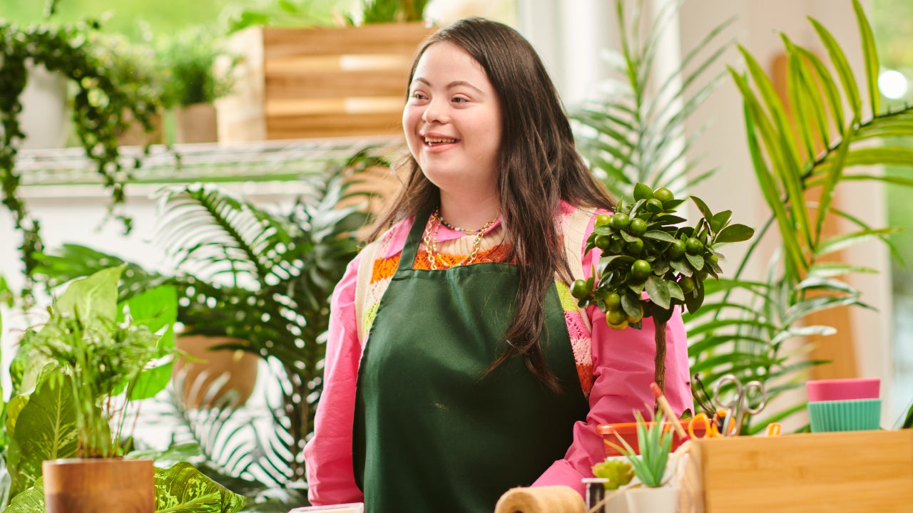 A florist stands in her shop, smiling.