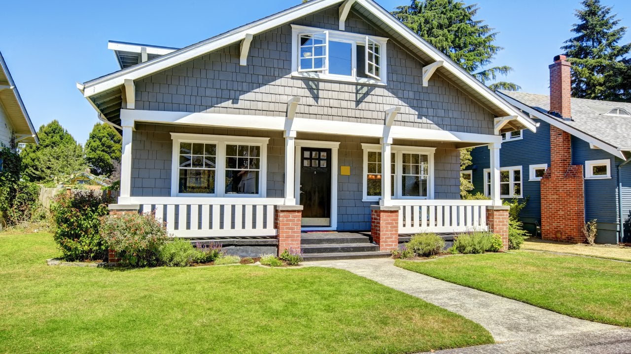 Clapboard siding house exterior. Large entance porch with brick trim and white railings