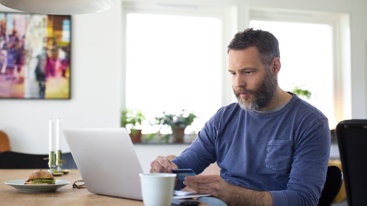 Businessman paying through credit card on laptop at home