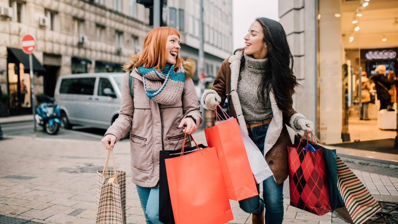 Happy two girls holding bunch of shopping bags