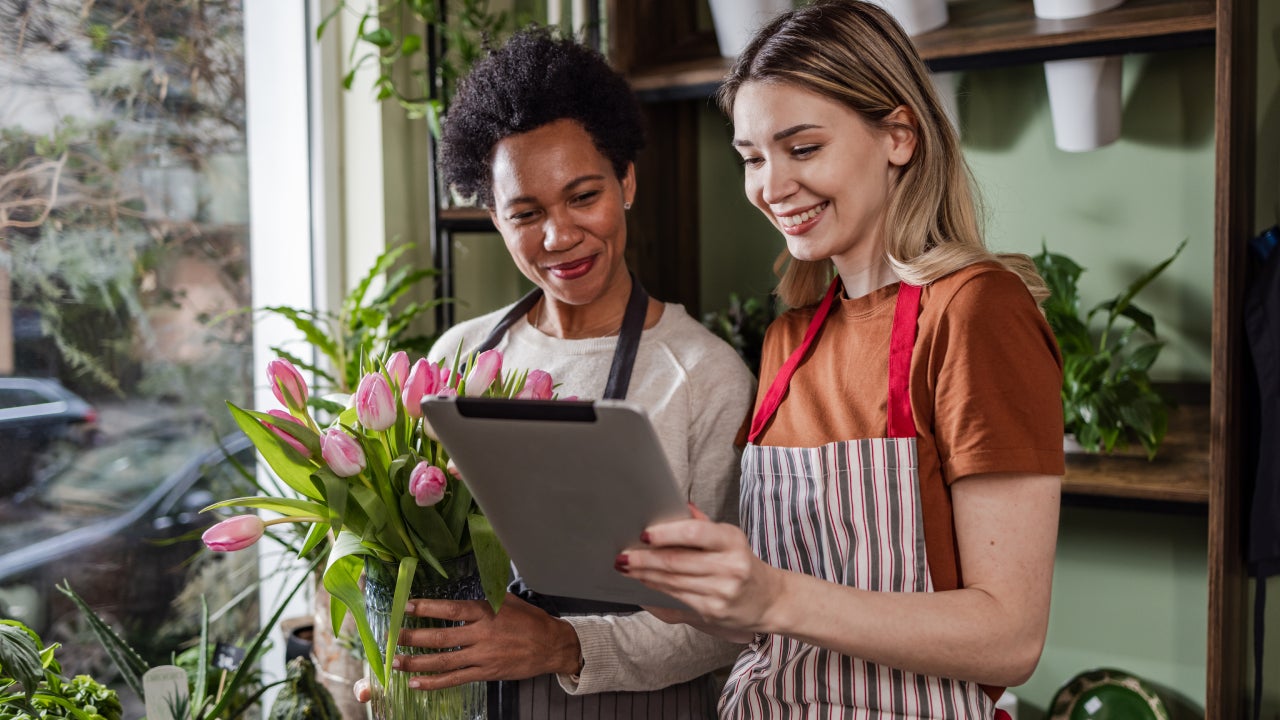 Two women using digital tablet in their flower workshop